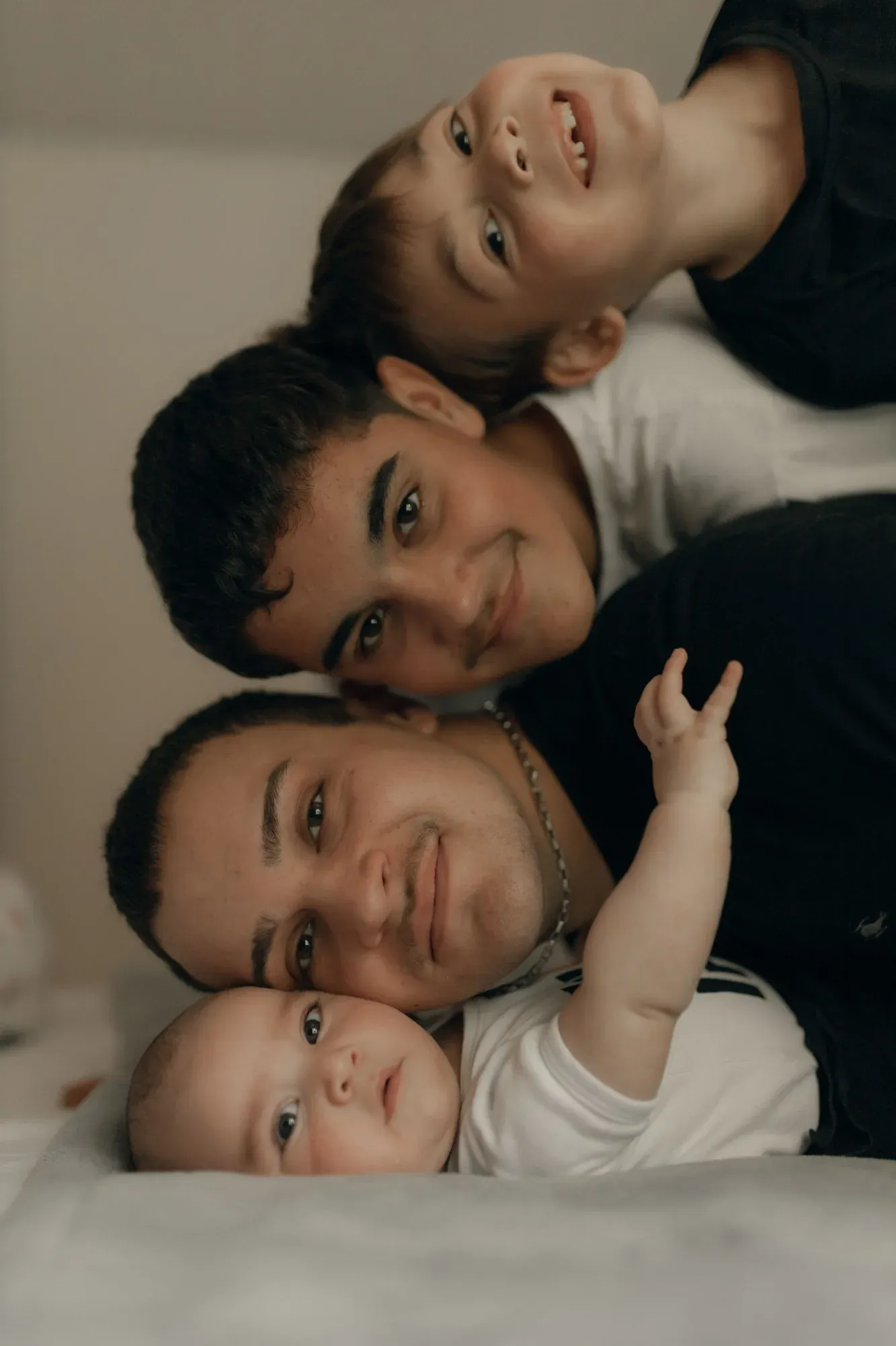 Un bébé, deux enfants et un jeune homme allongés tête contre tête, souriants