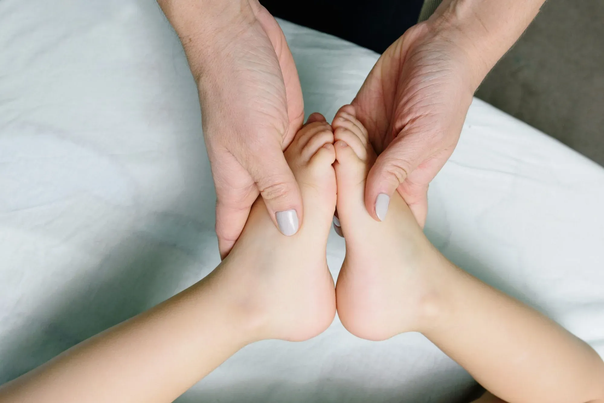 Des mains qui tiennent et pressent doucement les deux pieds d’un enfant